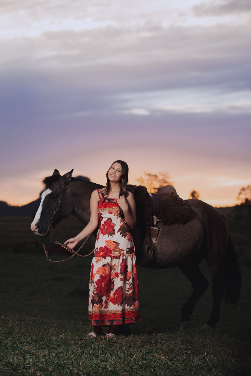 Foto da aniversariante Ryanna ao lado de um cavalo ao entardecer